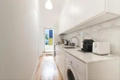 a white kitchen with a sink and a microwave at Tripas-Coração, Santa Teresa in Porto