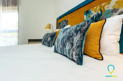 a bedroom with a white bed with yellow and blue pillows at Camilo Apartment in Porto