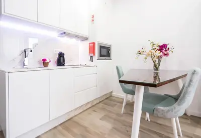 a kitchen with white cabinets and a table and chairs at HM - Nearby Bolhão Studio in Porto