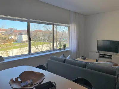 a living room with a couch and a tv and windows at Ninon- Premium Trindade by Porto City Hosts in Porto