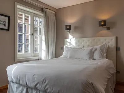 a bedroom with a large white bed with two windows at Guest House Douro in Porto