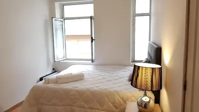 a bedroom with a bed with a lamp and two windows at Oporto Beauty Flat in Porto