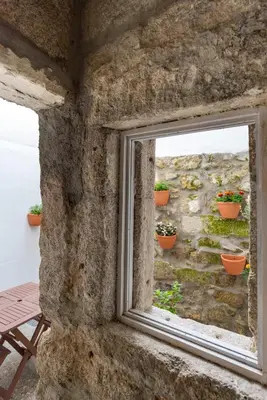 a window in a stone wall with potted plants at ZD Moreira Flats A By PortoProperties4You in Porto