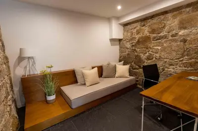a couch in a room with a stone wall at Stay In Apartments - D. Hugo 23 in Porto