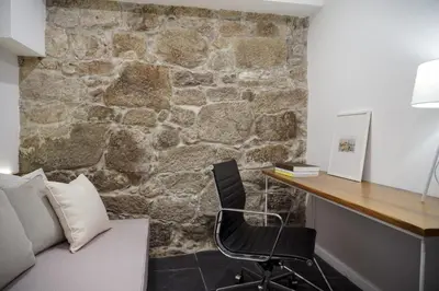 a bedroom with a stone wall with a desk and a chair at Stay In Apartments - D. Hugo 23 in Porto