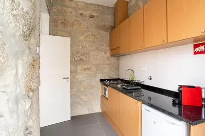 a kitchen with wooden cabinets and a stone wall at ZD Moreira Flats C By PortoProperties4You in Porto