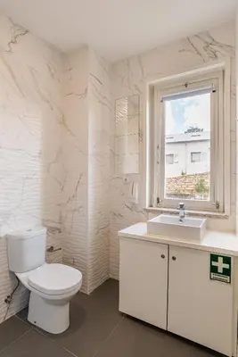 a white bathroom with a toilet and a window at ZD Moreira Flats E By PortoProperties4You in Porto