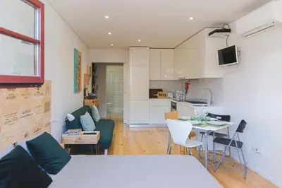a bedroom with a white bed and a kitchen at APOSENTUS - The Wine Studio in Porto