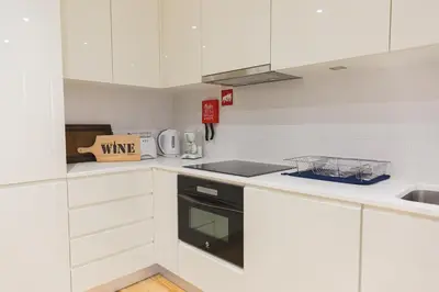 a white kitchen with white cabinets and a sink at APOSENTUS - The Wine Studio in Porto