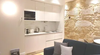 a dining room with a stone wall and a table and chairs at Wonderful Porto Design Apartments in Porto