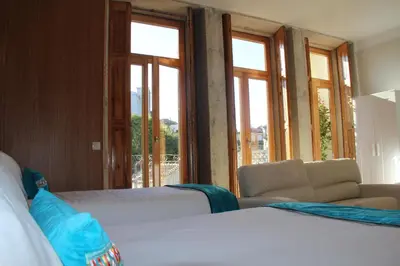 a bedroom with two beds and a couch and windows at Loulé Estúdios in Porto