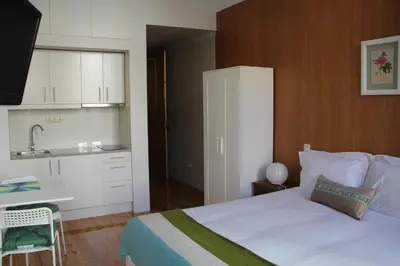 a bedroom with a large bed and a kitchen at Loulé Estúdios in Porto