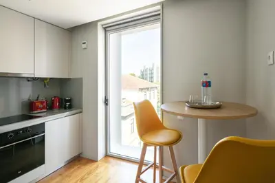 a kitchen with a counter and a table and a window at Porto Insight Cedofeita- Parking, Balconies & AC in Porto