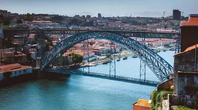 a blue bridge over a river with a city at Porto Insight Cedofeita- Parking, Balconies & AC in Porto