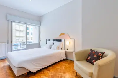 a white bedroom with a bed and a chair at UNIQUE Modernist Duplex apartment & PARKING in Porto