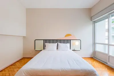 a white bed in a room with a large window at AMAZING DUPLEX - Mid Century Experience & PARKING in Porto