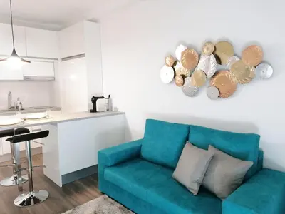 a living room with a blue couch and a kitchen at Window Garden Apartment in Porto