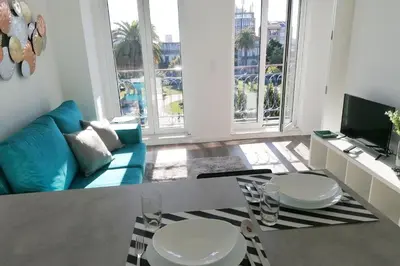 a living room with two white tables and a blue couch at Window Garden Apartment in Porto
