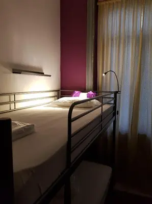 a room with bunk beds and a table and a chair at By Doors Hostel in Porto