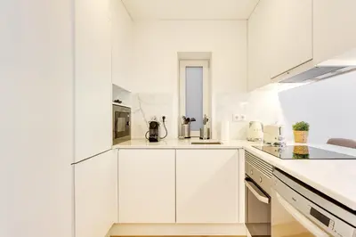 a white kitchen with white cabinets and appliances at Wood Premium Downtown Apartment by DA'HOME in Porto