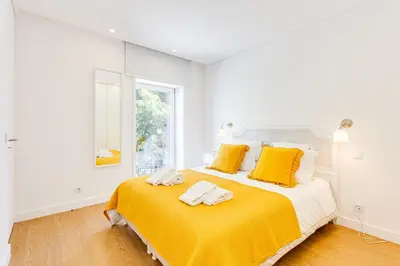 a white bedroom with a large bed with yellow pillows at Wood Premium Downtown Apartment by DA'HOME in Porto