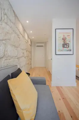 a living room with a couch and a stone wall at Liiiving in Porto - Charming Downtown Delight in Porto