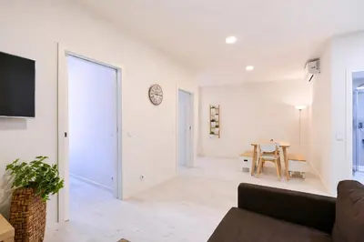 a bedroom with a white bed and a kitchen at FindMe InPorto Santa Catarina in Porto