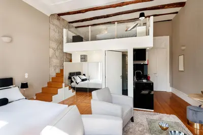 a loft apartment with a white bed and a living room at Maison Cabral in Porto