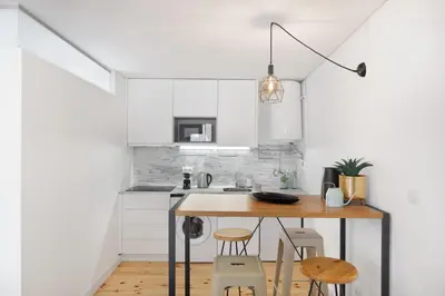a white kitchen with a wooden table and chairs at Relax Porto Studio by Own Places in Porto