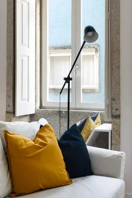 a floor lamp sitting next to a couch with pillows at Spacious Duplex in Porto's Downtown • A/C in Porto