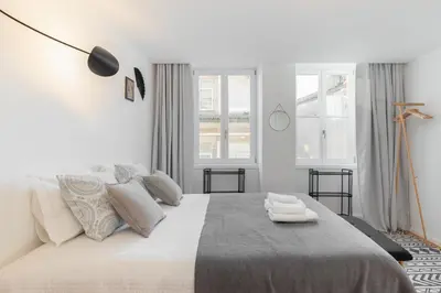 a white bedroom with a large bed with two towels on it at Porto Historical Center Apartments in Porto