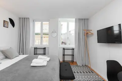 a white bedroom with a bed and a flat screen tv at Porto Historical Center Apartments in Porto