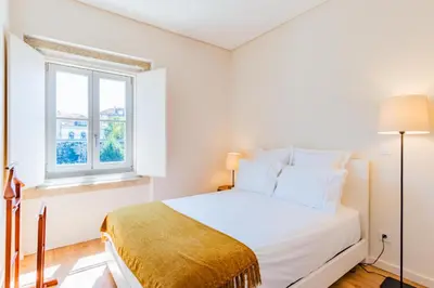 a white bedroom with a bed and a window at Boavista Garden Apartment in Porto
