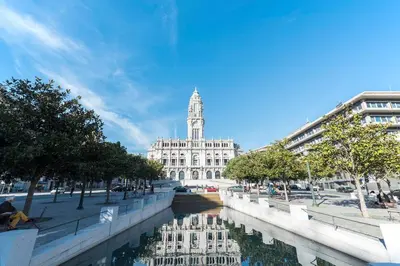a building with a clock tower and a river in a city at Boavista Garden Apartment in Porto