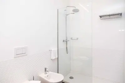 a white bathroom with a shower and a sink at VIVA Size Flats Clérigos in Porto