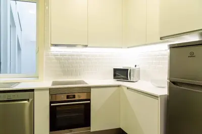a kitchen with white cabinets and a microwave at VIVA Size Flats Clérigos in Porto