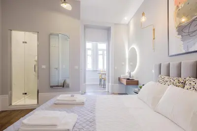 a white bedroom with a large bed and a walk in shower at Plaza-Charming GuestHouse in Porto