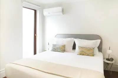 a white bedroom with a large white bed with pillows at Trindade Premium Apartments in Porto