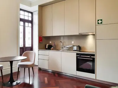 a kitchen with white cabinets and a table at Trindade Premium Apartments in Porto