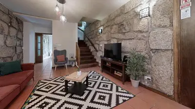a living room with a stone wall and a tv at Vivenda Center Porto in Porto