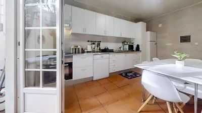 a kitchen with white cabinets and a table and chairs at Vivenda Center Porto in Porto