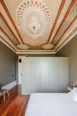 a bedroom with a white bed and a coffered ceiling at Menina Colina Guesthouse in Porto