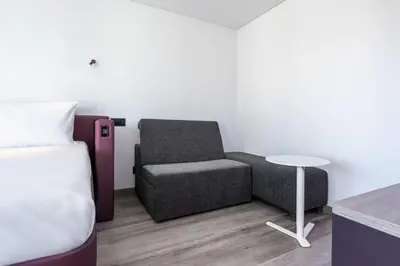 a bedroom with a bed and a chair and a table at YOTEL Porto in Porto