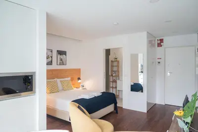 a white bedroom with a bed and a chair at Sunflower Luxury Loft w AC Downtown and Metro in Porto