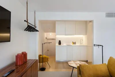 a living room with a kitchen with white cabinets at S.Bento Residences in Porto