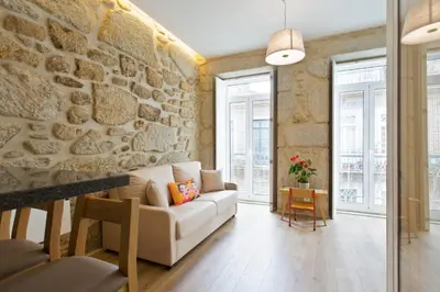a living room with a stone wall and a couch at Estrela de Gaia Apartments in Vila Nova de Gaia