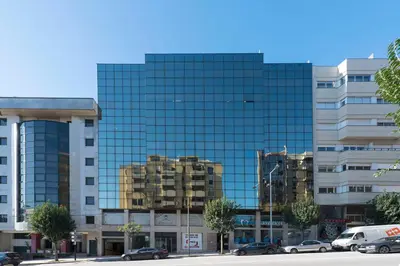 a tall glass building with cars parked in front of it at Oporto Dinis Apartment - Rooftop in Porto