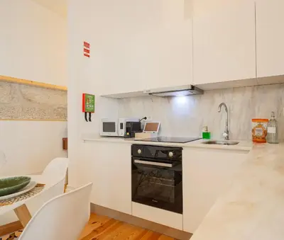 a kitchen with white cabinets and a sink and a stove at Esmeralda Apartment by Cozy Stay in Porto