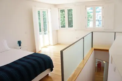 a white room with a bed and a staircase at Alfandega Apartments in Porto