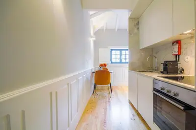 a kitchen with white cabinets and a chair in it at Barão Oporto Apartments in Porto